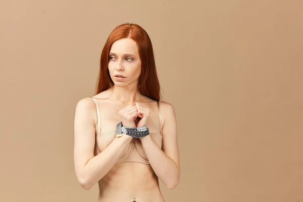 Femme aux cheveux roux avec un ruban à mesurer autour des poignets utilisé comme menottes — Photo