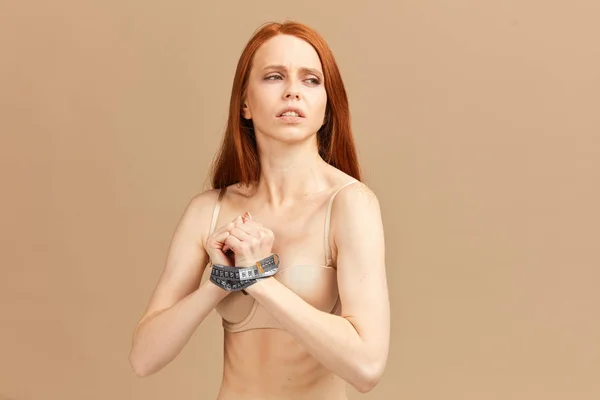 Červenovlasá žena s měřicí páskou kolem zápěstí, používaná jako pouta — Stock fotografie
