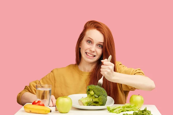 Comic grimacing funny woman on healthy food eating with broccoli and vegetables — Stock Photo, Image