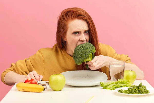 Овочева дієта. Сумна нудна жінка тримає броколі на виделці, роблячи похмурість — стокове фото