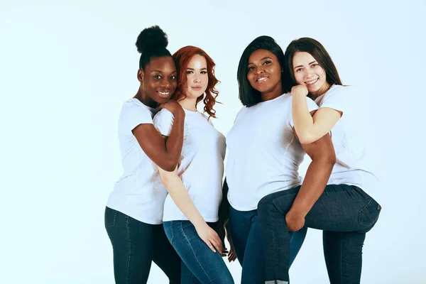 Two multicultural couples of women in casuals looking happy together on white — Stock Photo, Image