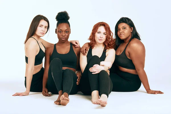 Multiracial females with different size and ethnicity stand together and smile. — Stock Photo, Image