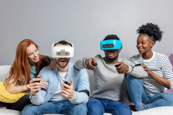 Twee jongens spelen video-games met behulp van Vr bril en vriendinnen steunen hen. — Stockfoto