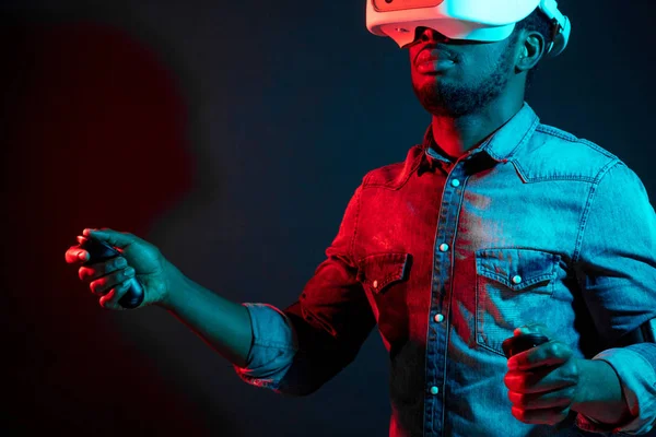 African Man in bianco, indossando VR Headset su sfondo rosso e blu doppio colore . — Foto Stock