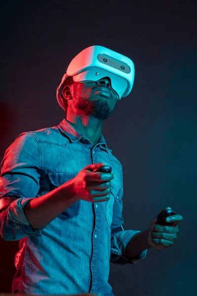 African Man in bianco, indossando VR Headset su sfondo rosso e blu doppio colore . — Foto Stock