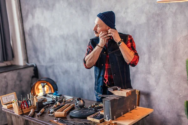 Young craftsman tring on earring after repairing it — Stock Photo, Image