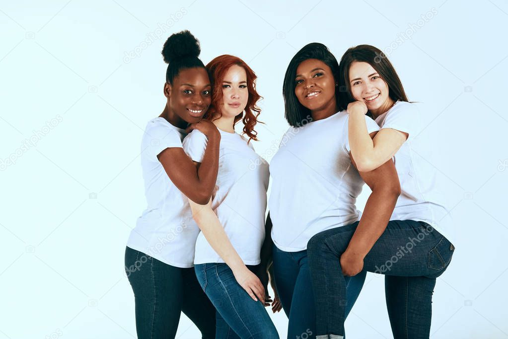 Two multicultural couples of women in casuals looking happy together on white