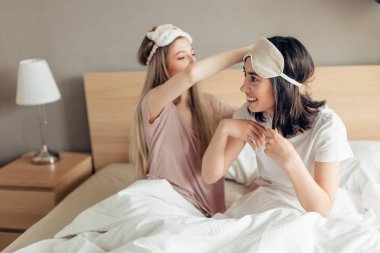 baş göz maskesi ile yatakta oturan güzel mutlu kadınlar