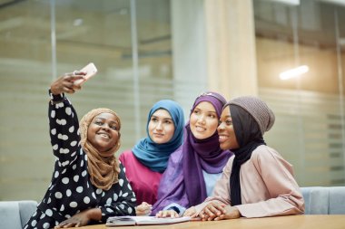 Asyalı Müslüman kadınlar bir seminer sırasında akıllı telefondan bilgi paylaşıyorlar