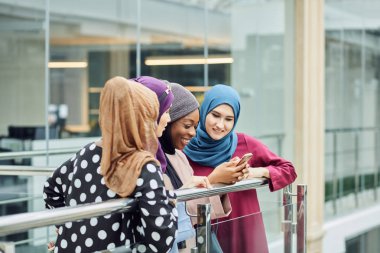 Farklı etnik kökenlere sahip bir grup İslamcı kadın telefonda birlikte izliyor.