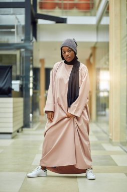 Müslüman tarzı, modern şapkalı, pembe elbiseli çekici Afrikalı kadın.