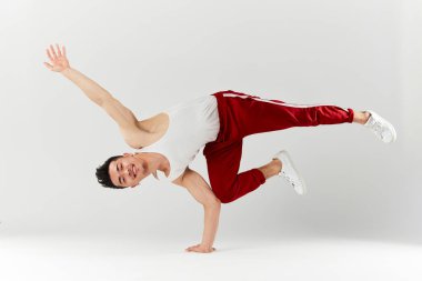 Asyalı break dansçı eğitmeni beyaz arka planda amuda kalkıyor.