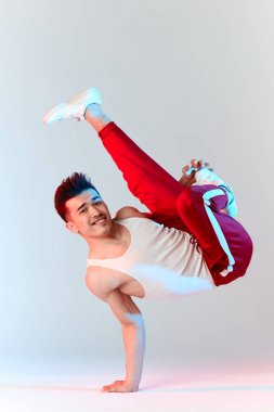 Asya Bboy dondurucu dublörde baş aşağı duruyor havada bacaklarla dengede duruyor.