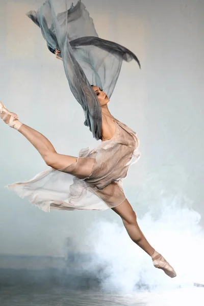 Μπαλαρίνα φορώντας γκρίζα διαφανή ρούχα άλμα επί σκηνής με αποτέλεσμα καπνό — Φωτογραφία Αρχείου
