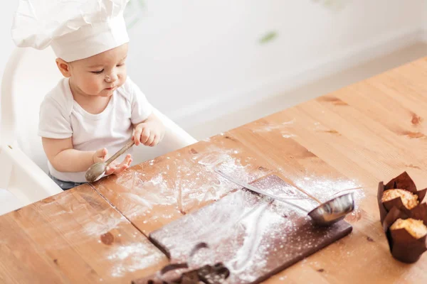 Infant cook baby portrait wearing white chef hat at kitchen table — Stock Photo, Image