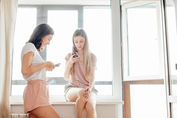 Twee aantrekkelijke ontzagwekkende zusters texting messegas, SMS naar hun vriendjes — Stockfoto