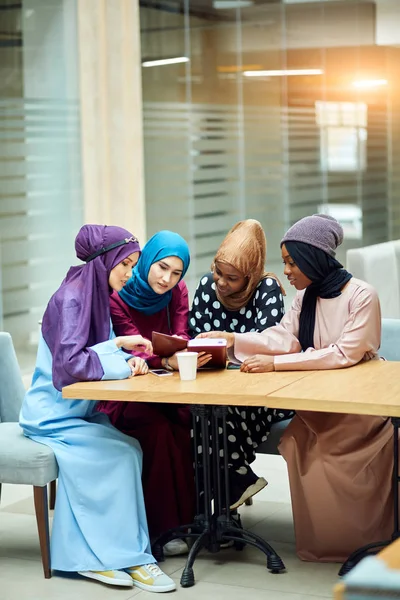 Fröhliche junge arabische Studentinnen lesen Buch im Café. — Stockfoto