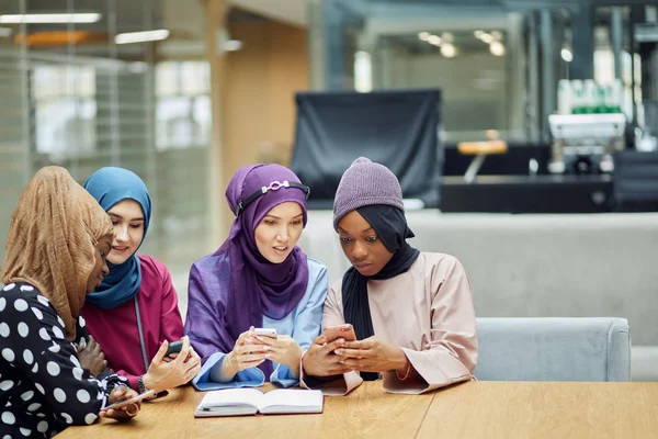 Arabische jonge vrouwen kijken op mobiele telefoon muzikale video clip staan samen. — Stockfoto