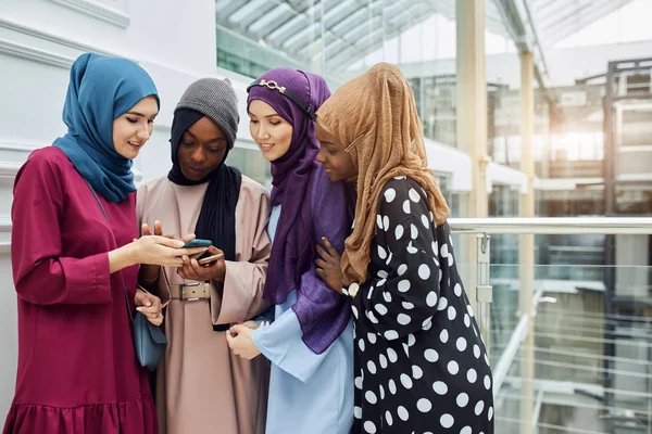 Grupo multiétnico musulmán de chicas mira el teléfono inteligente en la mano de la mujer africana — Foto de Stock