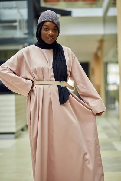 Glamorous african woman dressed in muslim style pink dress with modern hat