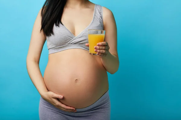 Mladý svlečený těhotná žena s velkým bříškem drží sklenici šťávy — Stock fotografie