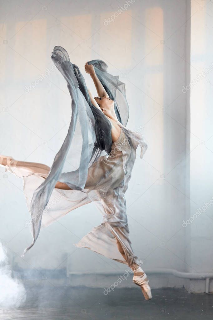 Flexible ballet dancer stretching in the dark lighted studio