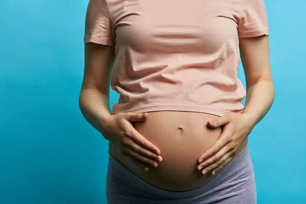 9ヶ月のエキサイティングな期待を背負った妊婦は、彼女のおなかを保持します — ストック写真