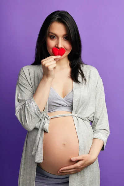 Amar a la mujer embarazada sosteniendo su vientre mientras posa en el estudio — Foto de Stock
