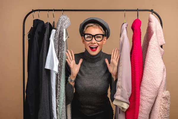 Glückliches Mädchen, das zwischen hängenden Kleidern steht — Stockfoto