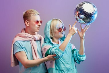 Mor arka planda disko topuyla poz veren genç moda dansçıları.