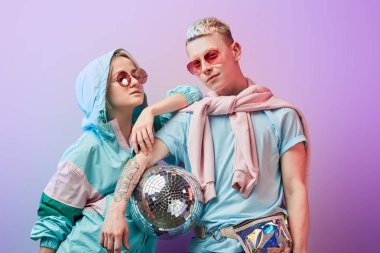 Mor arka planda disko topuyla poz veren genç moda dansçıları.