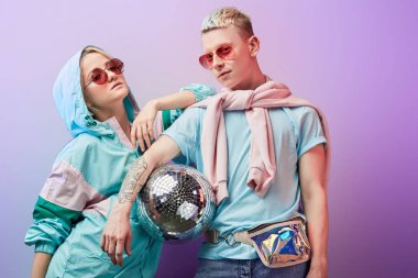 Mor arka planda disko topuyla poz veren genç moda dansçıları.