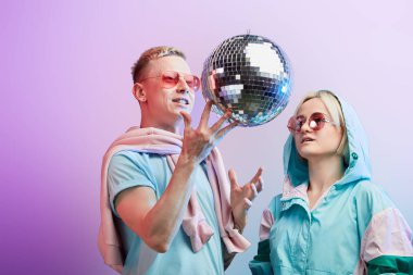 Mor arka planda disko topuyla poz veren genç moda dansçıları.