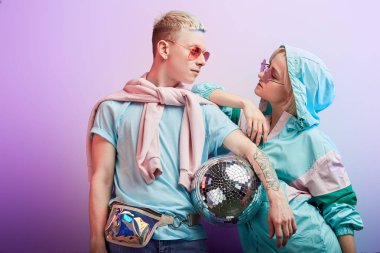 Mor arka planda disko topuyla poz veren genç moda dansçıları.