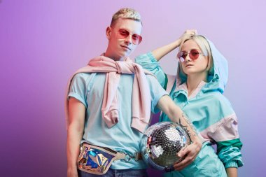 Mor arka planda disko topuyla poz veren genç moda dansçıları.