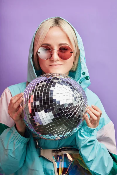 Блондинка-хипстер позирует с сияющей дискотекой на фиолетовом фоне — стоковое фото