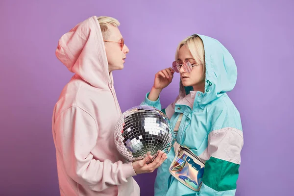 Joven pareja de bailarines de moda posando con bola disco sobre fondo violeta —  Fotos de Stock