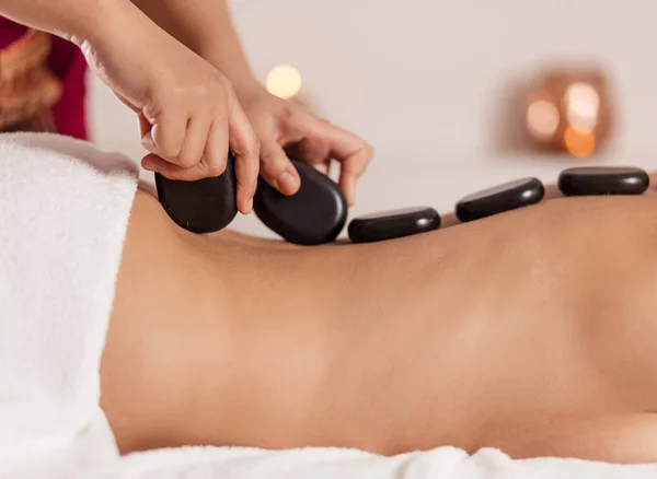 Masseur putting black stones on the cliens back — Stock Photo, Image