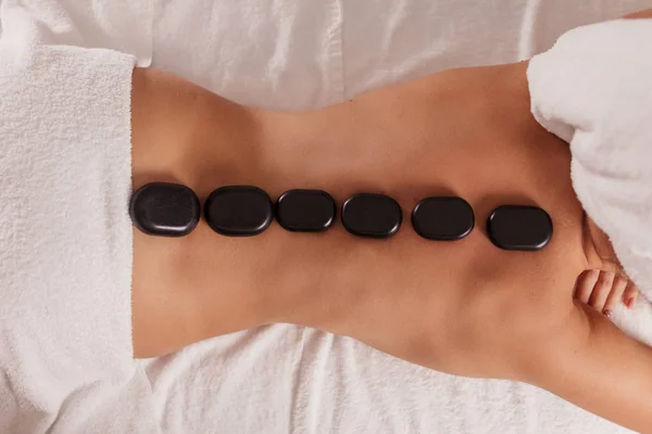Giovane donna magra ottenere massaggio con pietre calde — Foto Stock