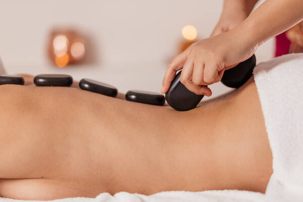 каменная терапия в спа салоне.женщина с горячими базальтовыми камнями
