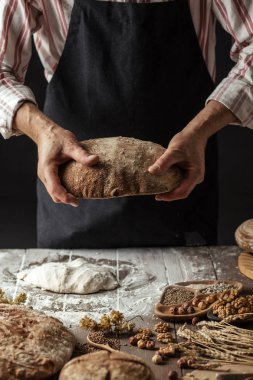 Tanınmayan baker taze pişmiş rustik organik somun ekmek elinde tutan