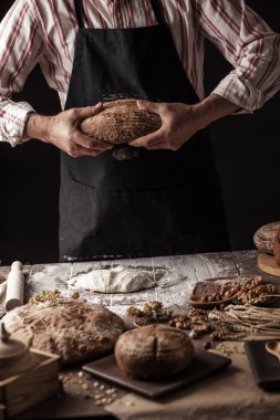 Tanınmayan baker taze pişmiş rustik organik somun ekmek elinde tutan
