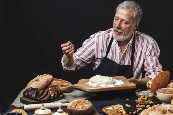 Volwassen bebaarde baker man kneden van deeg voor een brood op tafel — Stockfoto