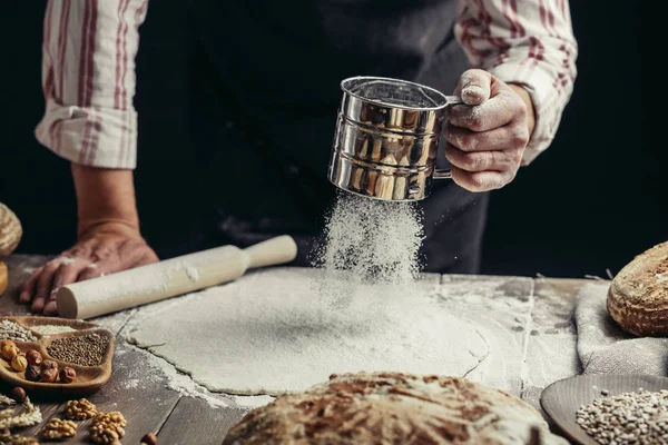 Homem polvilhando um pouco de farinha na massa. Mãos amassando massa, vista cortada — Fotografia de Stock