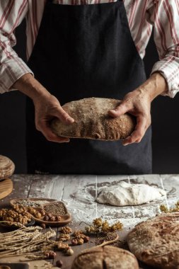 Tanınmayan baker taze pişmiş rustik organik somun ekmek elinde tutan