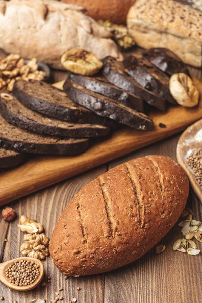 Whole grain multigrain bread, whole and sliced, contains seeds isolated on black — Stock Photo, Image