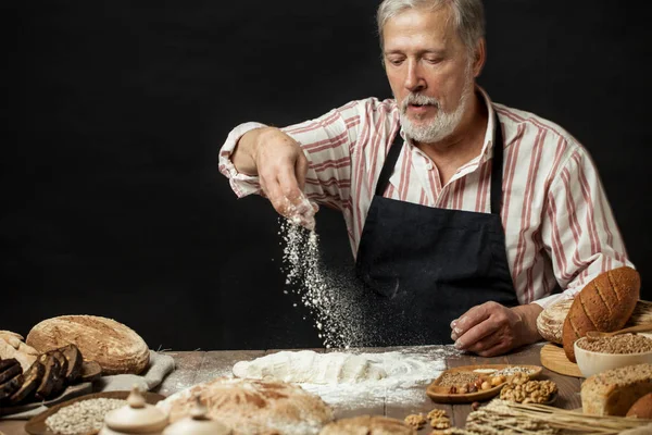 Man sprinkling some flour on dough. Hands kneading dough, cropped view