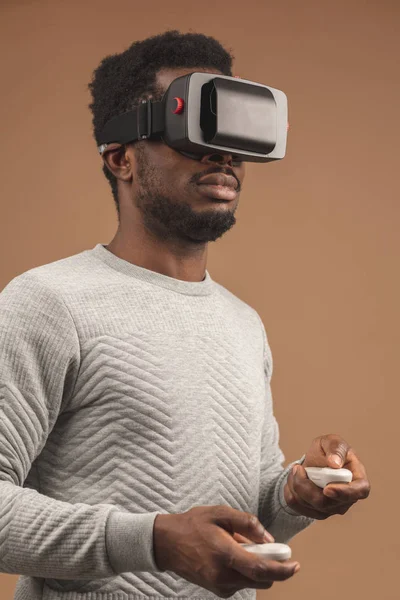 Black man wearing 3d vr glasses, playing videogame, holding joystick in hands