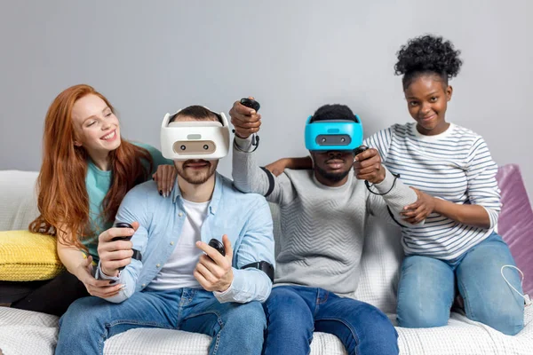 Dos chicos jugando videojuegos usando gafas VR y novias los apoyan . — Foto de Stock