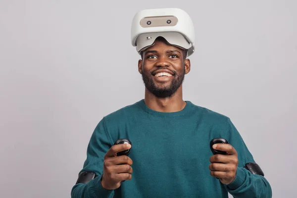 Uomo africano indossa occhiali realtà virtuale, tiene controller di gioco, isolato — Foto Stock